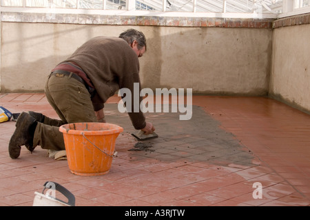 Verfugen einen Steinbruch geflieste Boden in einem viktorianischen Gewächshaus in Yorkshire Januar 2007 mit dunklen braunen Fugenmasse Stockfoto