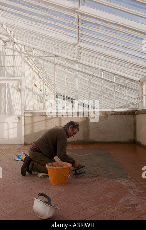 Verfugen einen Steinbruch geflieste Boden in einem viktorianischen Gewächshaus in Yorkshire Januar 2007 mit dunklen braunen Fugenmasse Stockfoto