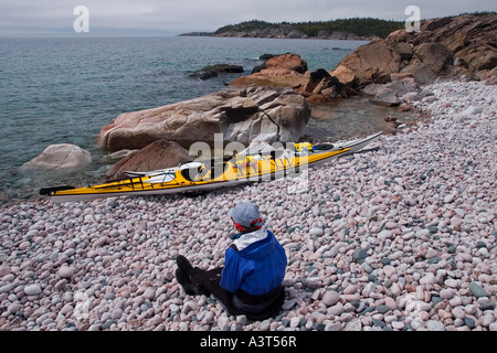 Ein Kajakfahrer Meer liegt in der Nähe von Booten auf einem Kiesstrand im Lake Superior Provincial Park in der Nähe von Wawa Ontario Kanada Stockfoto