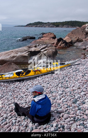 Ein Kajakfahrer Meer liegt in der Nähe von Booten auf einem Kiesstrand im Lake Superior Provincial Park in der Nähe von Wawa Ontario Kanada Stockfoto