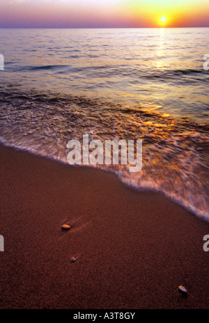 SUNSET OVER LAKE SUPERIOR BEACH IN MICHIGAN ONTONAGON MIT WELLEN UND STEINEN Stockfoto