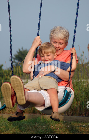 Zweisamkeit Großmutter spielen mit Kleinkind Jungen auf einer Schaukel lächelnd Stockfoto