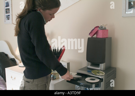 Teenager-Mädchen unter CDs von Halter zu CD-Player zulegen Stockfoto