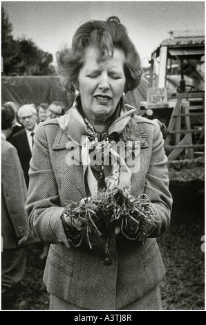 Frau Thatcher komischen Gesicht ziehen, wie sie Gülle auf einem Bauernhof abholt Stockfoto