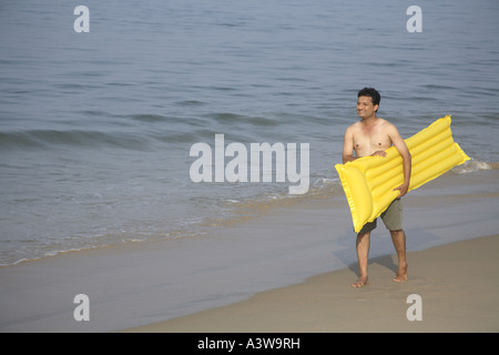 Mann mit schwimmenden Kunststoffbett am Strand im Urlaub genießen Stockfoto