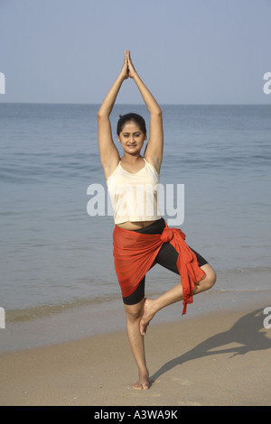 Frauen im Urlaub ausüben, dabei stehen Yoga Asanas am Strand Stockfoto