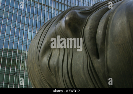 Moderne Skulptur eines menschlichen Kopf und Gesicht in Canary Wharf in London mit einem Glas ummauerten Büro Hochhaus Wolkenkratzer Stockfoto