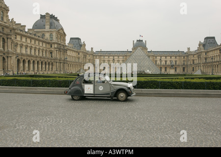 Eine sehr französische Szene als Citroen 2cv passiert das Louvre Museum über die Straße Place du Carrousel in Paris. Stockfoto
