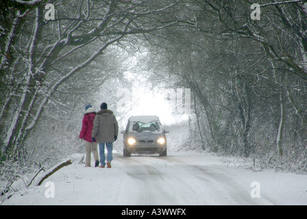 Passanten in Feldweg bei Schneefall Bewegung über die Mitnahme von Pkw ermöglichen übergeben Scheinwerfer eingeschaltet Stockfoto