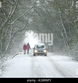 Passanten in Feldweg bei Schneefall Bewegung über die Mitnahme von Pkw ermöglichen übergeben Scheinwerfer eingeschaltet Stockfoto