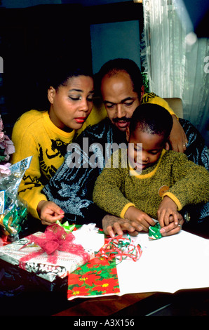 Afrikanische amerikanische Eltern Alter 40 helfende Sohn 6 Jahre wickeln Weihnachtsgeschenke. St Paul Minnesota USA Stockfoto