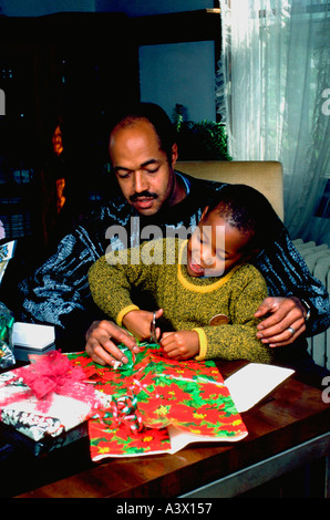 African American Vater Alter 40 helfende Sohn 6 Jahre wickeln Weihnachtsgeschenke. St Paul Minnesota USA Stockfoto