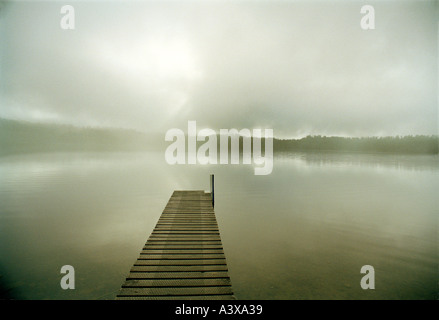 Ein starker Sonnenstrahl bricht durch niedrige Wolkendecke reflektiert in einem See auf der Südinsel, Neuseeland Stockfoto