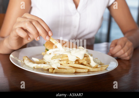 Eine junge Frau, Essen, Burger und Pommes frites Stockfoto