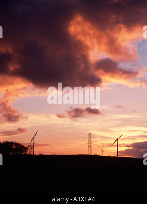 Windräder und Hochspannungsmasten bei Sonnenuntergang, England, UK. Stockfoto