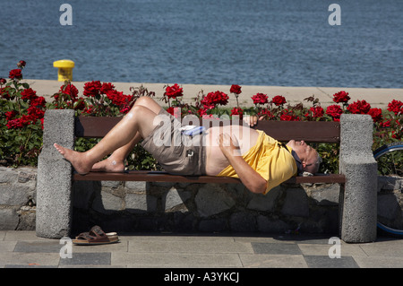 Ein großer Mann schlafen auf einer Bank am Meer in Polen Stockfoto