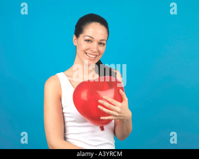 Junge Frau mit farbigen aufgeblasene Luftballons vor einem blauen Hintergrund alleine fertig werden, für eine Party oder Feier Veranstaltung Stockfoto