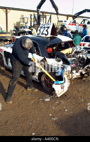 Mann mit einem Vorschlaghammer zu reparieren ein altes Auto nach einem Banger-Rennen Stockfoto