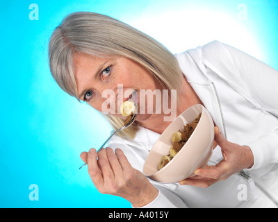 Reife Frau essen Müsli mit Banane-Modell veröffentlicht Stockfoto