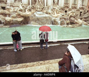 Touristen fotografieren und mit Sonnenschirmen am Trevi-Brunnen in Rom Stockfoto