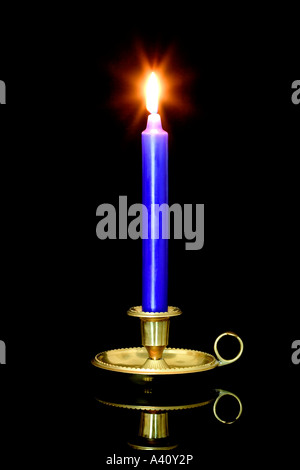 Blaue Kerze und Flamme in einen Messing Kerzenständer auf einem schwarzen Hintergrund mit Reflexion Stockfoto