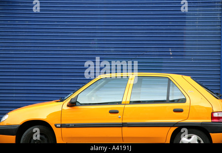 gelbes Auto vor blauen garage Stockfoto