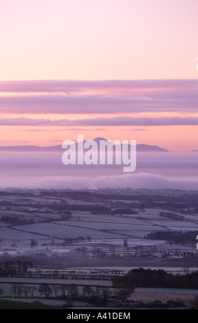 Eine atmosphärische nebligen frostige Winterlandschaft aus Burnswark Hügel mit Blick über Solway Firth zu Skiddaw in der Nähe von Sunrise Schottland Stockfoto