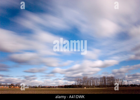 winterliche Landschaft mit Feld und düstere kleine Holz und weißen Wolken verwischt beim driften in der Nähe von Bayern München Stockfoto