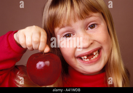 Kleines Mädchen hält Apfel fehlende Frontzähne Stockfoto