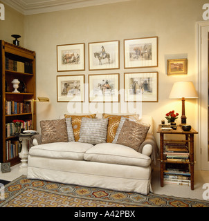 Sahne Sofa mit neutralen gemusterten Kissen unter Bilder an Wänden in traditionellen Gartenhaus Stockfoto