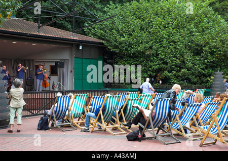 Die Menschen sitzen in Liegestühlen Jazz zur Mittagszeit in einem zentralen London Park zu hören. Stockfoto