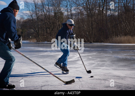 Zwei Männer spielen Eishockey auf einem zugefrorenen Teich Stockfoto