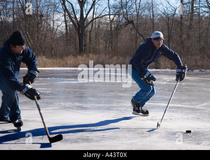 Zwei Männer spielen Eishockey auf einem zugefrorenen Teich Stockfoto