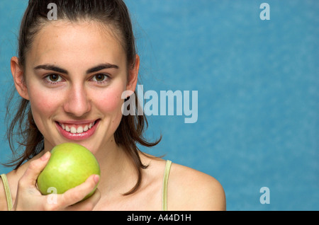 Lächelnde junge Frau hält Apfel Stockfoto
