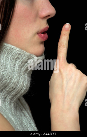 Junge Frau mit Finger, Lippen schließen, Seitenansicht Stockfoto