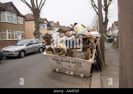 Nicht lizenziert und überlastet Skip in der Straße voller DIY Müll außerhalb Haus zu verkaufen oder verkauft Haus in Chingford North East London Stockfoto