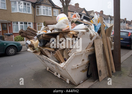 Nicht lizenziert und überlastet Skip in der Straße voller DIY Müll außerhalb Haus zu verkaufen oder verkauft Haus in Chingford North East London Stockfoto