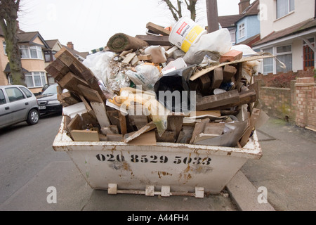 Unerlaubte und überladenen Skip in Straße, voll von DIY Müll außerhalb Haus zu verkaufen oder verkauft Haus in Chingford North East London Stockfoto