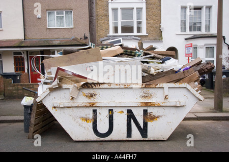 Nicht lizenziert und überlastet Skip in der Straße voller DIY Müll außerhalb Haus zu verkaufen oder verkauft Haus in Chingford North East London Stockfoto