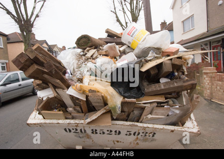 Nicht lizenziert und überlastet Skip in der Straße voller DIY Müll außerhalb Haus zu verkaufen oder verkauft Haus in Chingford North East London Stockfoto