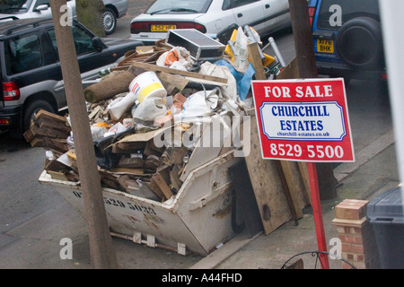 Nicht lizenziert und überlastet Skip in der Straße voller DIY Müll außerhalb Haus zu verkaufen oder verkauft Haus in Chingford North East London Stockfoto