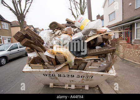 Nicht lizenziert und überlastet Skip in der Straße voller DIY Müll außerhalb Haus zu verkaufen oder verkauft Haus in Chingford North East London Stockfoto