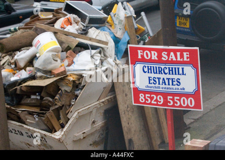 Nicht lizenziert und überlastet Skip in der Straße voller DIY Müll außerhalb Haus zu verkaufen oder verkauft Haus in Chingford North East London Stockfoto