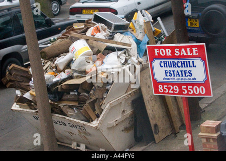 Nicht lizenziert und überlastet Skip in der Straße voller DIY Müll außerhalb Haus zu verkaufen oder verkauft Haus in Chingford North East London Stockfoto