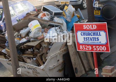 Nicht lizenziert und überlastet Skip in der Straße voller DIY Müll außerhalb Haus zu verkaufen oder verkauft Haus in Chingford North East London Stockfoto