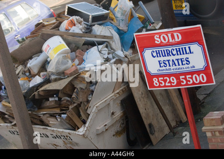 Nicht lizenziert und überlastet Skip in der Straße voller DIY Müll außerhalb Haus zu verkaufen oder verkauft Haus in Chingford North East London Stockfoto