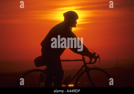 Silhouette Profil, ein Mann sitzt auf einem Zyklus bei Sonnenuntergang. Stockfoto