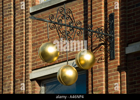 Pfandhaus Nahaufnahme von traditionellen Zeichen der drei goldenen Kugeln über Pfandleiher Geschäftslokale auf ornamentalen Eisen Halterung England UK unterstützt Stockfoto