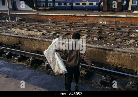 ein Kind Rag Picker sammelt Flaschen und Papier in seinen Sack am Bahnhof New Delhi, Indien Stockfoto