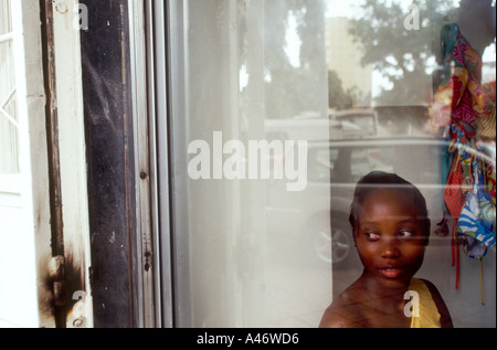Eine junge modisch gekleidete junge Frau arbeitet in einem Geschäft Uhren die teuren Autos fahren die Straßen von Luanda, Angola Stockfoto